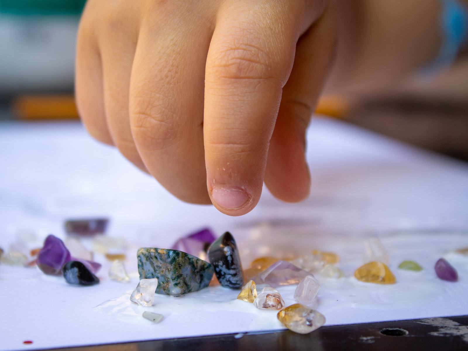 dettaglio della mano di un bambino che prende delle pietrine colorate durante un laboratorio didattico al museo